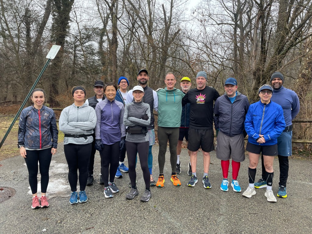 Runners across tree background at Forbidden Drive trailhead below horse stables